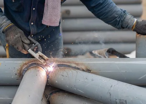 Worker welding pole structure for park roof in factory. Stock Photos