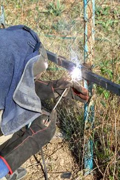 Worker welds metal pipes with electrode welding outdoors 스톡 사진
