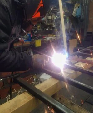 A worker welds a metal structure using a welding machine and an electrode. The 스톡 사진