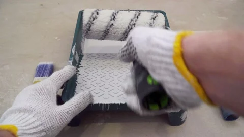 Worker wets paint roller and prepares for painting Stock Footage 125710102