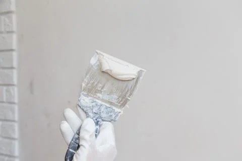 Worker in white gloves performs plastering of the walls of the room. Stock Photos