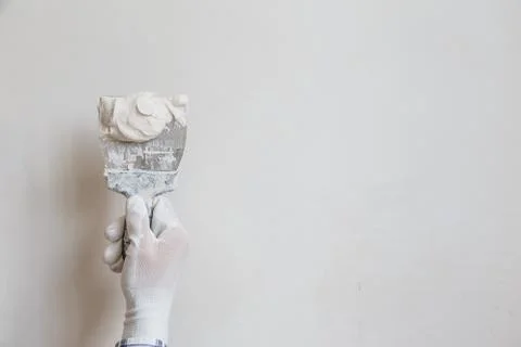 Worker in white gloves performs plastering of the walls of the room. Stock Photos