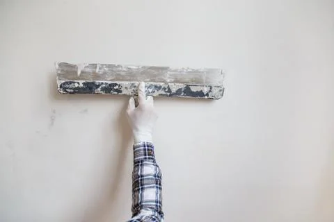 Worker in white gloves performs plastering of the walls of the room. Stock Photos