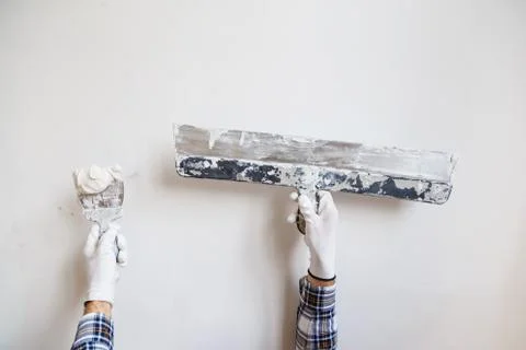 Worker in white gloves performs plastering of the walls of the room. Stock Photos