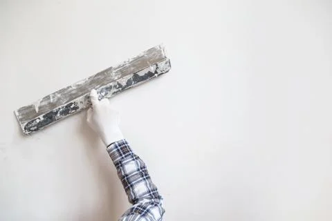 Worker in white gloves performs plastering of the walls of the room. Stock Photos