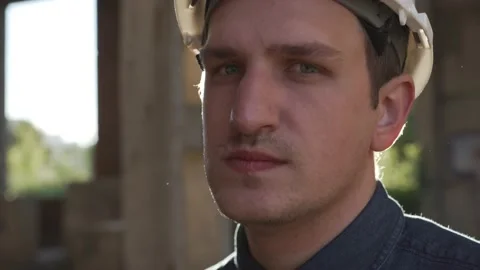 Worker in a white helmet on construction site turns to camera and puts on mask, Stock Footage 138075105