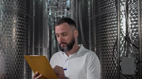Worker in a white polo shirt with a beard at a wine production plant Stock Footage 270058291