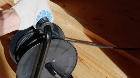 A worker winds an electrical wire on a black reel standing on a wooden floor 스톡 동영상 139338059