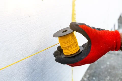 The worker winds the rope. Do-it-yourself sticking of foam insulation sheets  Stock Photos