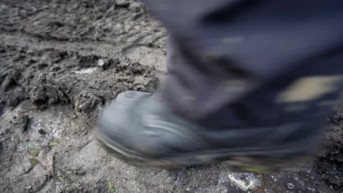 Worker in a working boots steps into the mud and leaves a footprint in mud Stock Footage 158976457
