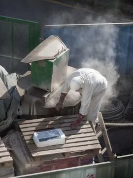 A worker is working  in the dust clouds with a machine for the production of  Stock Photos