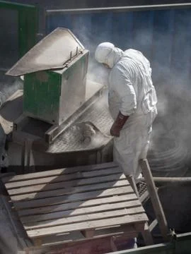 A worker is working  in the dust clouds with a machine for the production of  Stock Photos