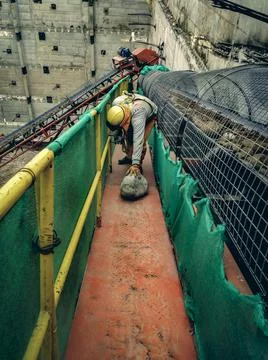 Worker working at height holding a stone with one hand while wearing a safety Photos
