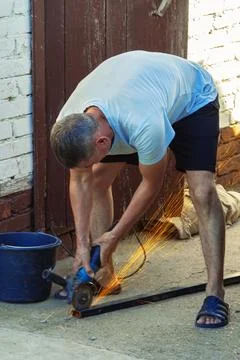 A worker works on an angle grinder. Sparks when handling metals. Metal processin Photos