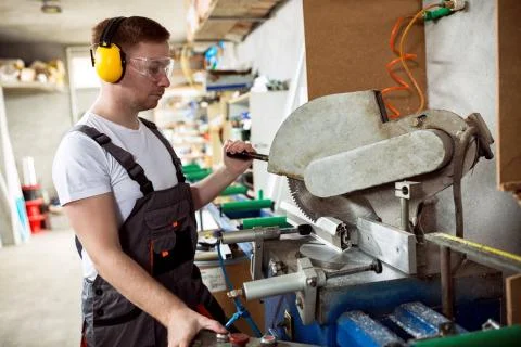 Worker in the workshop cuts pvc profile with circular saw Stock Photos