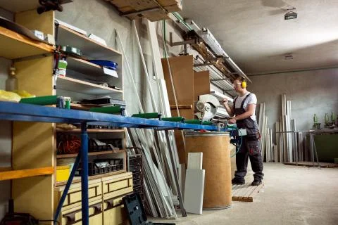 Worker in the workshop cuts the pvc profile Stock Photos