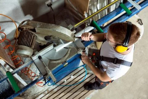 Worker in the workshop cuts the pvc profile with circular saw Stock Photos