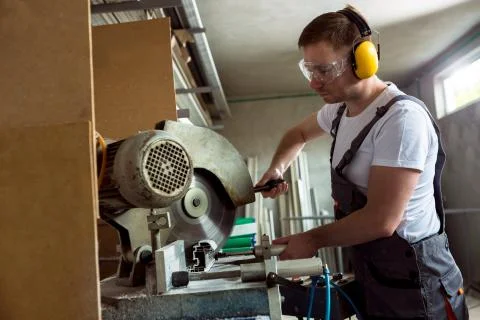 Worker in the workshop cuts pvc profile Stock Photos