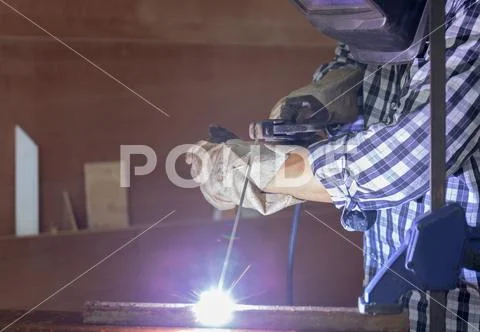 Worker in workwear welding the steel part by manual with safety equipment Stock Photos