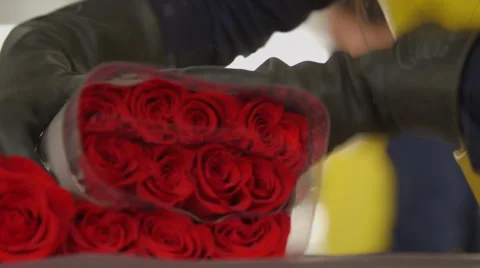 Worker wrapping red roses in plastic Stock Footage 50178510