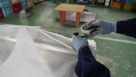 Worker wrapping stainless steel trash bin in bubble wrap for shipping packaging Stock Footage 345045820
