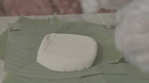 Worker wraps square cheese in banana leaves inside a factory Stock Footage 222015472