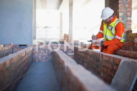 Worker Writing On Clipboard On Site