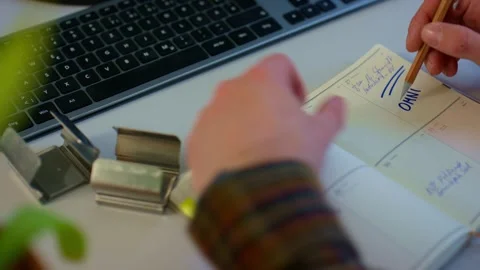 Worker Writing Notes On Paperwork Beside Computer Keyboard At Desk Stock Footage 338162810