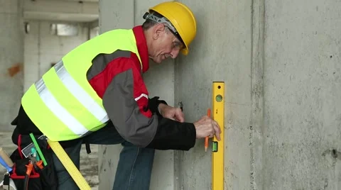 Worker in yellow hard hat with level at building plot Stock Footage 50600547