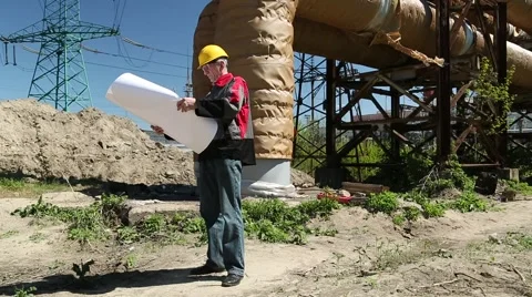Worker in yellow hard hat with project drawings at power station Stock Footage 63237990