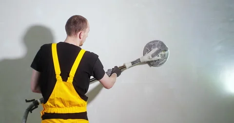 Worker in yellow work suit sanding the wall before painting using special Stock Footage 150723958