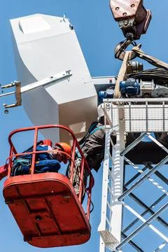 Workers on aerial platform with the help of a crane carry out the installation Stock Photos