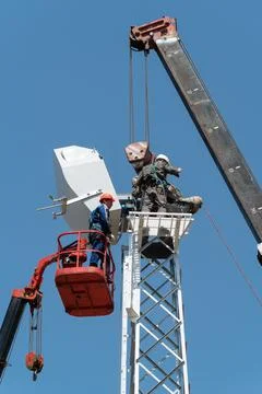 Workers on aerial platform with the help of a crane carry out the installation Stock Photos
