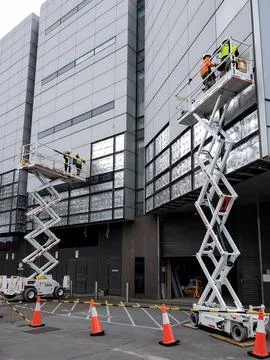 Workers on Aerial Work Platforms or Cherry Pickers replacing side building .. Stock Photos
