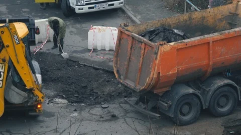 Workers and construction equipment work on the site of the repair of the road Видео 120197898