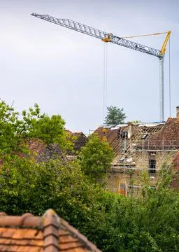Workers and crane removing old roof tiles from medieval house for renovatio.. Stock Photos