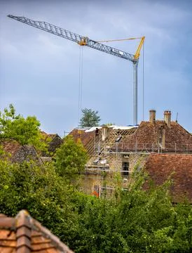 Workers and crane removing old roof tiles from medieval house for renovatio.. Stock Photos