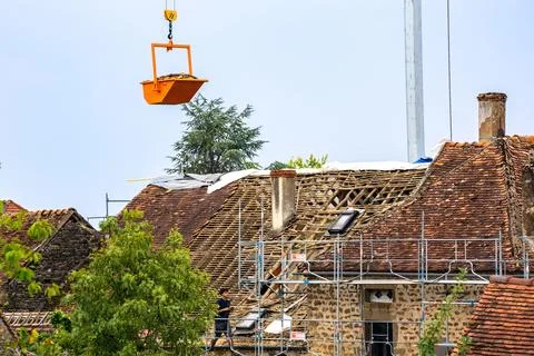 Workers and crane removing old roof tiles from medieval house for renovatio.. Stock Photos