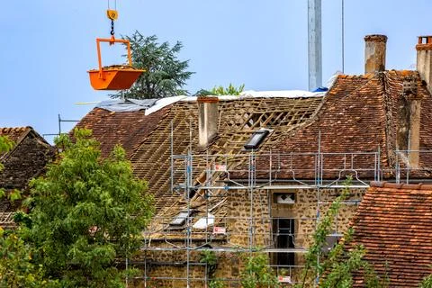 Workers and crane removing old roof tiles from medieval house for renovatio.. Stock Photos