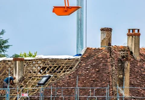 Workers and crane removing old roof tiles from medieval house for renovatio.. Stock Photos