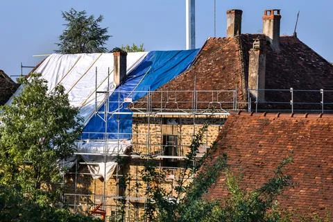 Workers and crane removing old roof tiles from medieval house for renovatio.. Stock Photos
