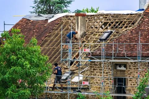 Workers and crane removing old roof tiles from medieval house for renovatio.. Stock Photos