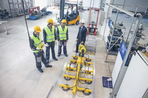 Workers and electro magnets lifting steel plate Stock Photos