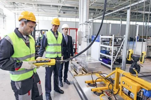 Workers and electro magnets lifting steel plate Stock Photos