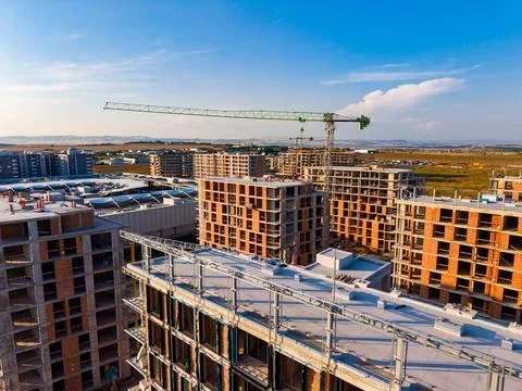 Workers and machinery are active at a construction site where multiple buildi Stock Photos
