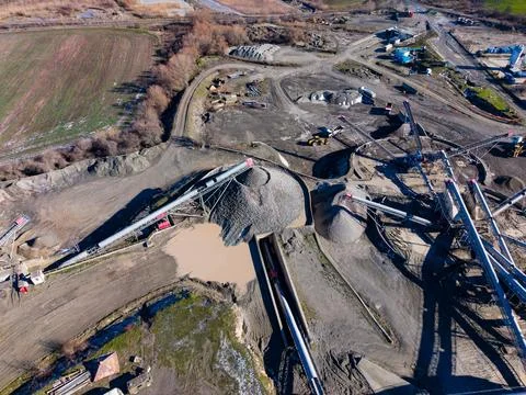 Workers and machines move and process raw materials at a construction site wh Stock Photos