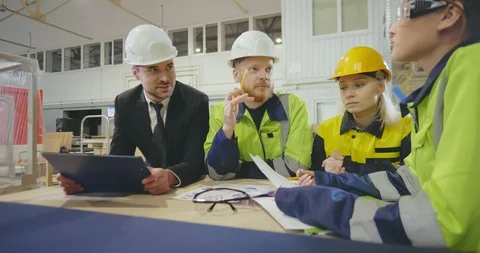 Workers and manager in safety helmets working with documents at factory Stock Footage 112062673