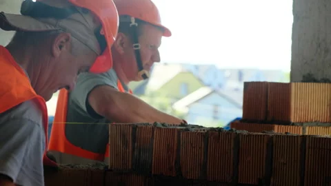 Workers apply mortar over material standing on construction site Stock Footage 317605967