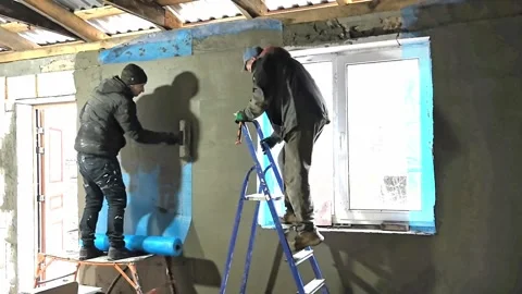 Workers apply paint to walls in a room during a renovation project at a building Vídeo Stock 326696441