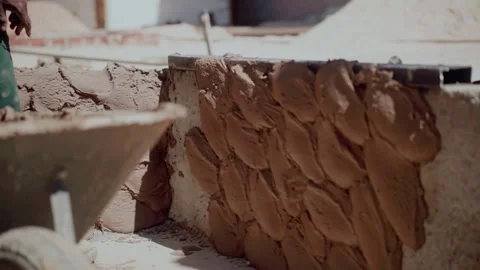 Workers applying cement and sand plaster to a rustic masonry wall during Stock Footage 343343134